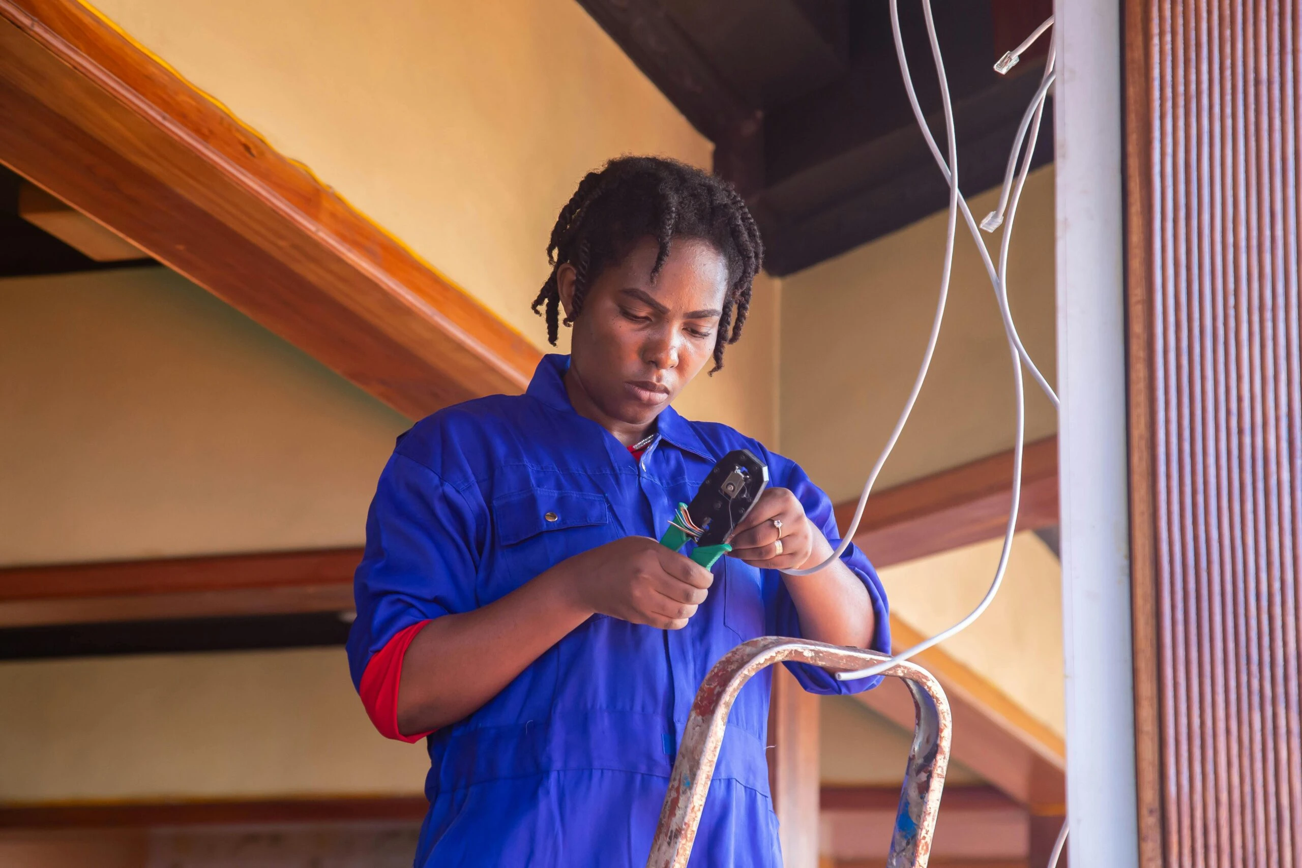 Woman in blue uniform focused on electrical task; reflects Kazar's Electric's commitment to safety and efficiency.